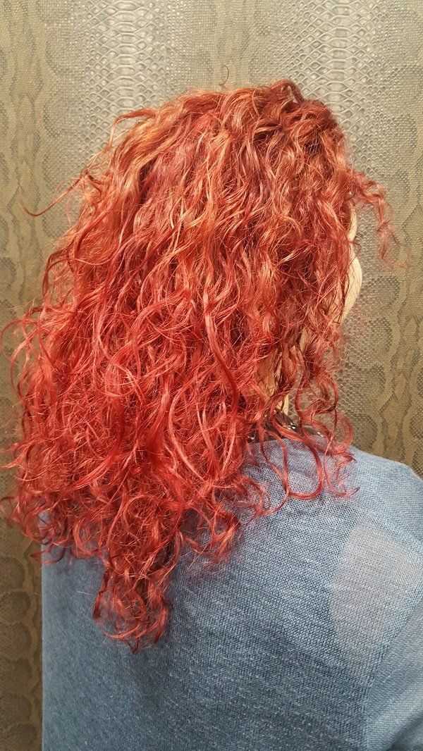 Una mujer con cabello rojo y rizado lleva un suéter azul.