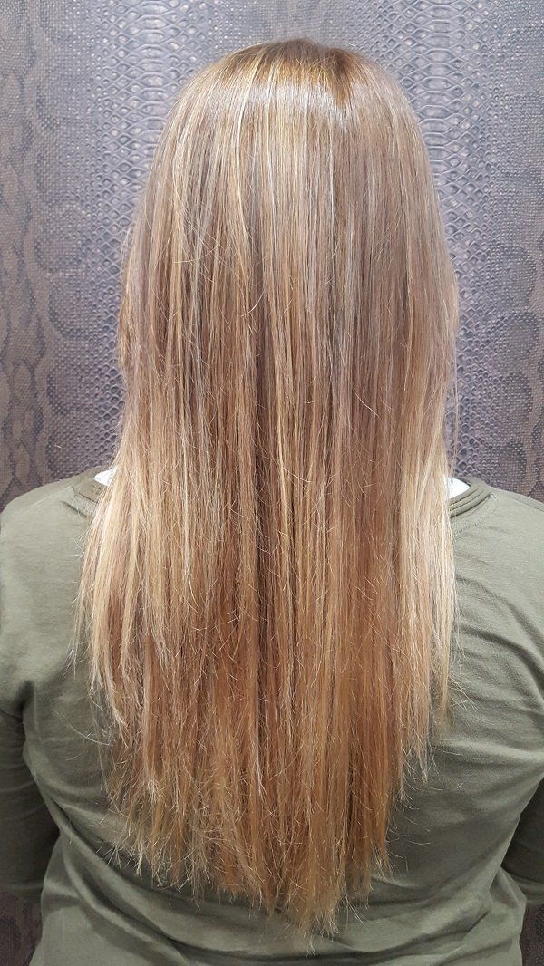 Una mujer con cabello largo y rubio lleva una camisa verde.