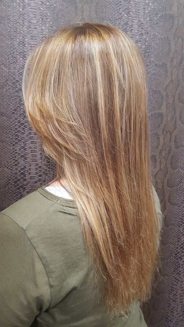 Una mujer con cabello largo y rubio lleva una camisa verde.