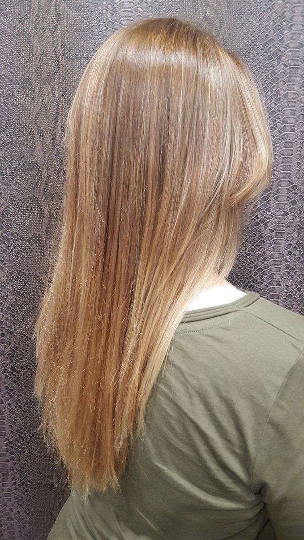 Una mujer con cabello largo y rubio lleva una camisa verde.