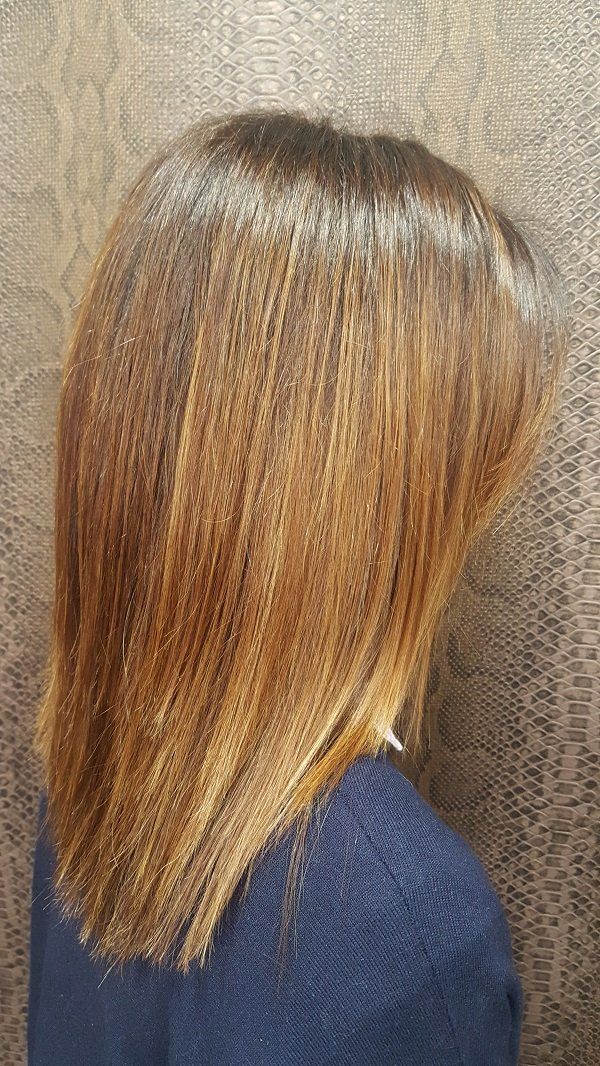 Una mujer con cabello largo y castaño lleva un suéter azul.