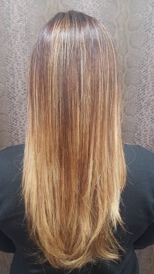 Una mujer con cabello largo y rubio está parada frente a una pared.