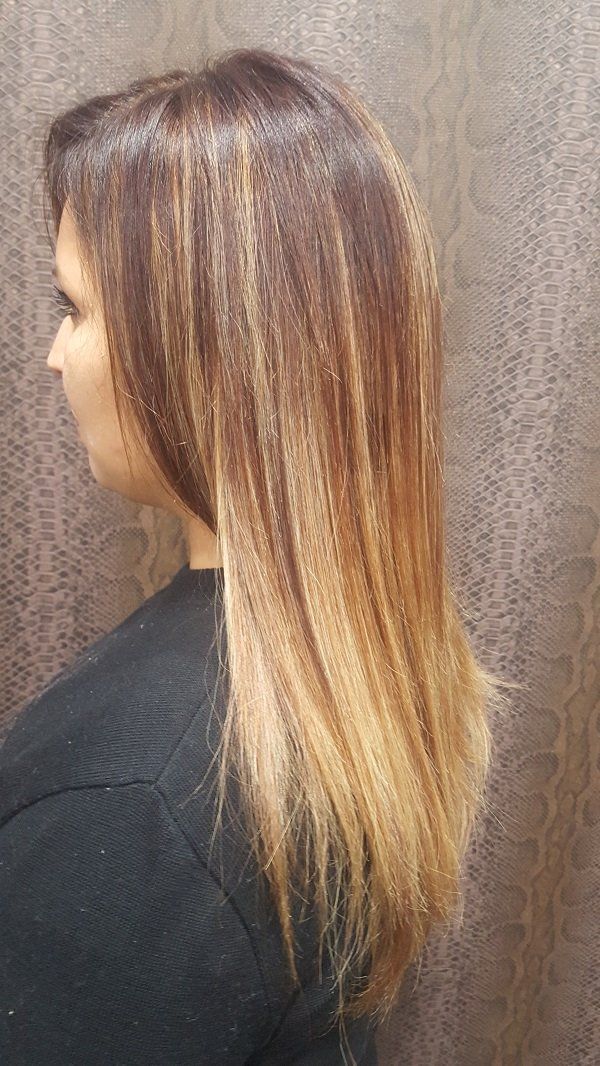 Una mujer con cabello largo lleva una camisa negra y está parada frente a una pared.