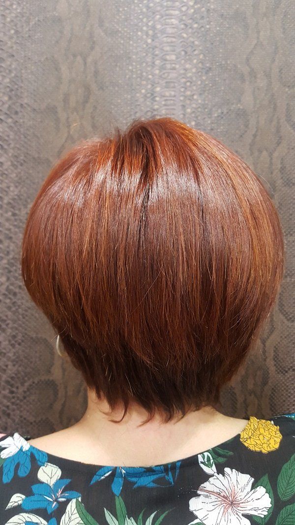 Una mujer con cabello corto y rojo lleva una camisa floreada.