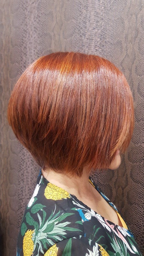 Una mujer con cabello corto y rojo lleva una camisa floreada.