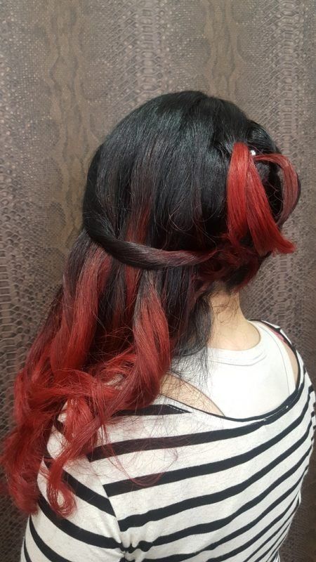 Una mujer con cabello negro y rojo lleva una camisa a rayas.