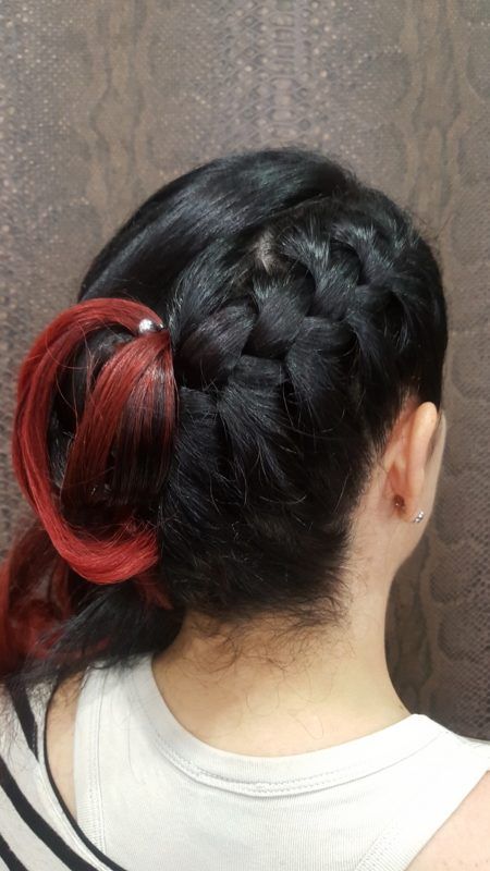 Una mujer con cabello negro y rojo lleva un moño trenzado.