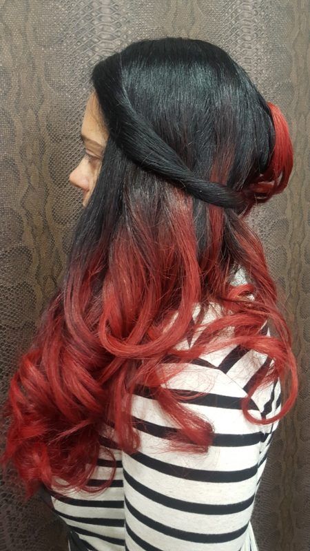 Una mujer con cabello negro y rojo lleva una camisa a rayas.