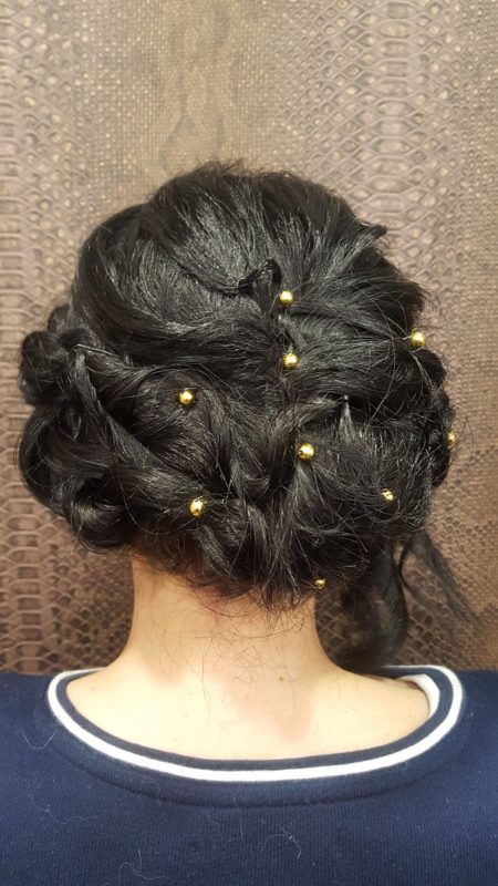 Una mujer lleva el pelo recogido en un moño con cuentas doradas.