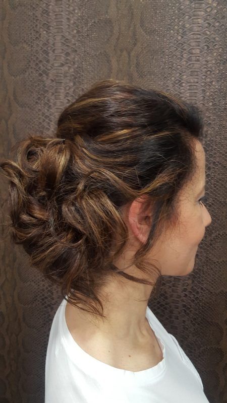 Una mujer con el pelo recogido en un moño lleva una camisa blanca.