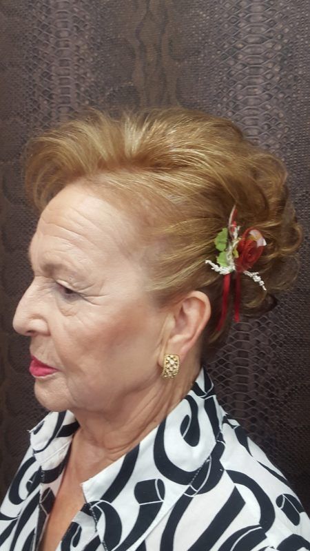 Una mujer con una flor en el pelo lleva una camisa blanca y negra.