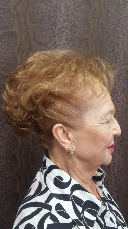 Una mujer con cabello rubio lleva una camisa blanca y negra y aretes.