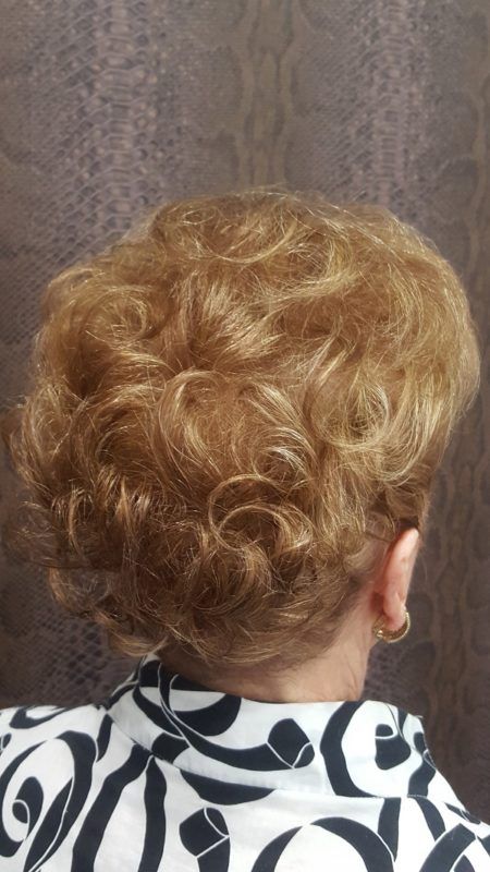 Una mujer con cabello rizado lleva una camisa blanca y negra.