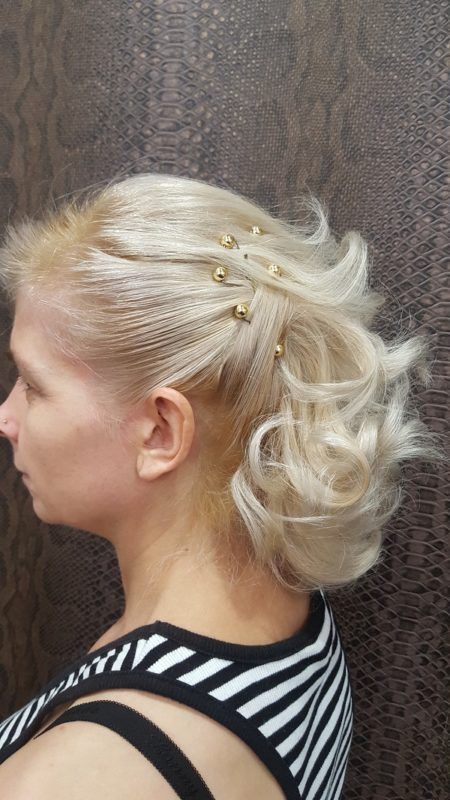 Una mujer con cabello rubio lleva una camisa de rayas y tiene el cabello recogido en un moño.