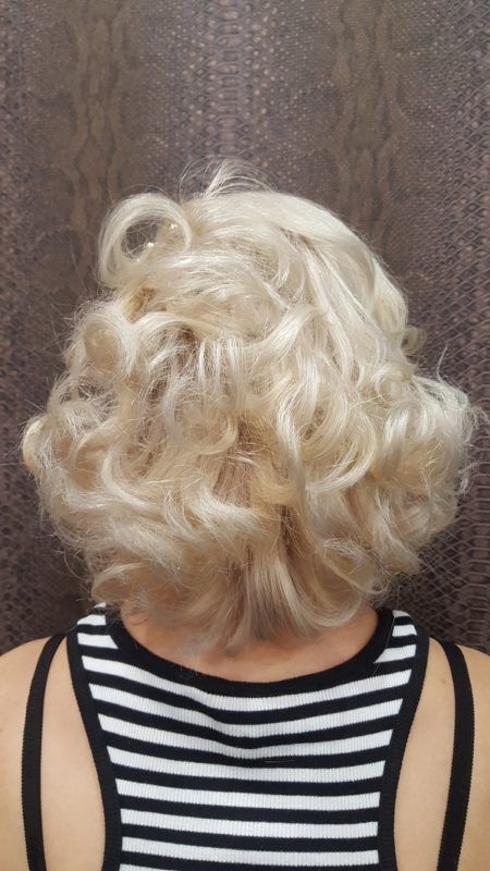 Una mujer con cabello rubio y rizado lleva una camiseta sin mangas de rayas blancas y negras.