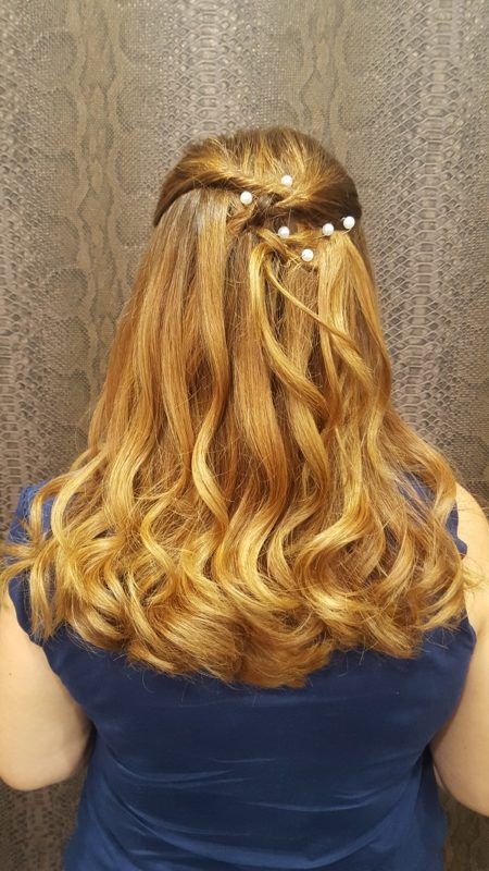 Una mujer con un vestido azul lleva el cabello recogido mitad arriba y mitad abajo con perlas.