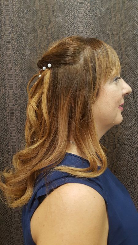 Una mujer con un vestido azul lleva el cabello recogido mitad arriba y mitad abajo.