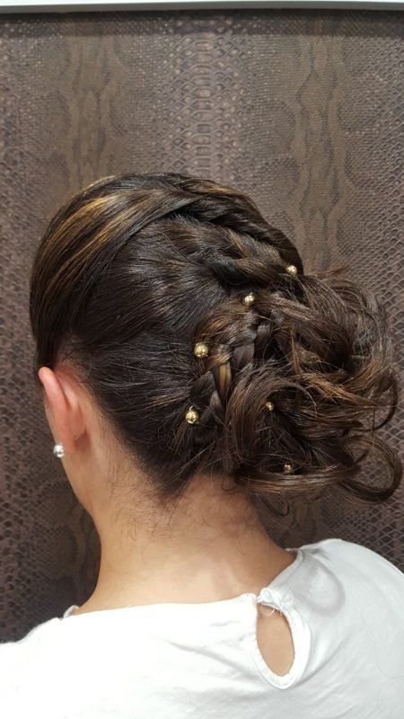 Una mujer lleva una camisa blanca y tiene el pelo recogido en un moño.