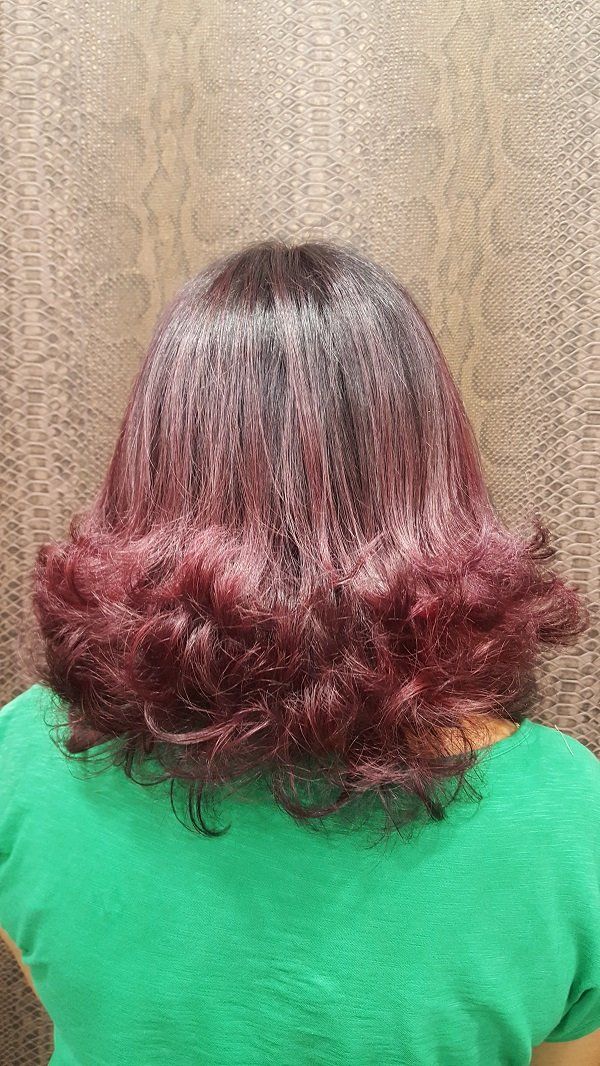 Una mujer con cabello rojo lleva una camisa verde.