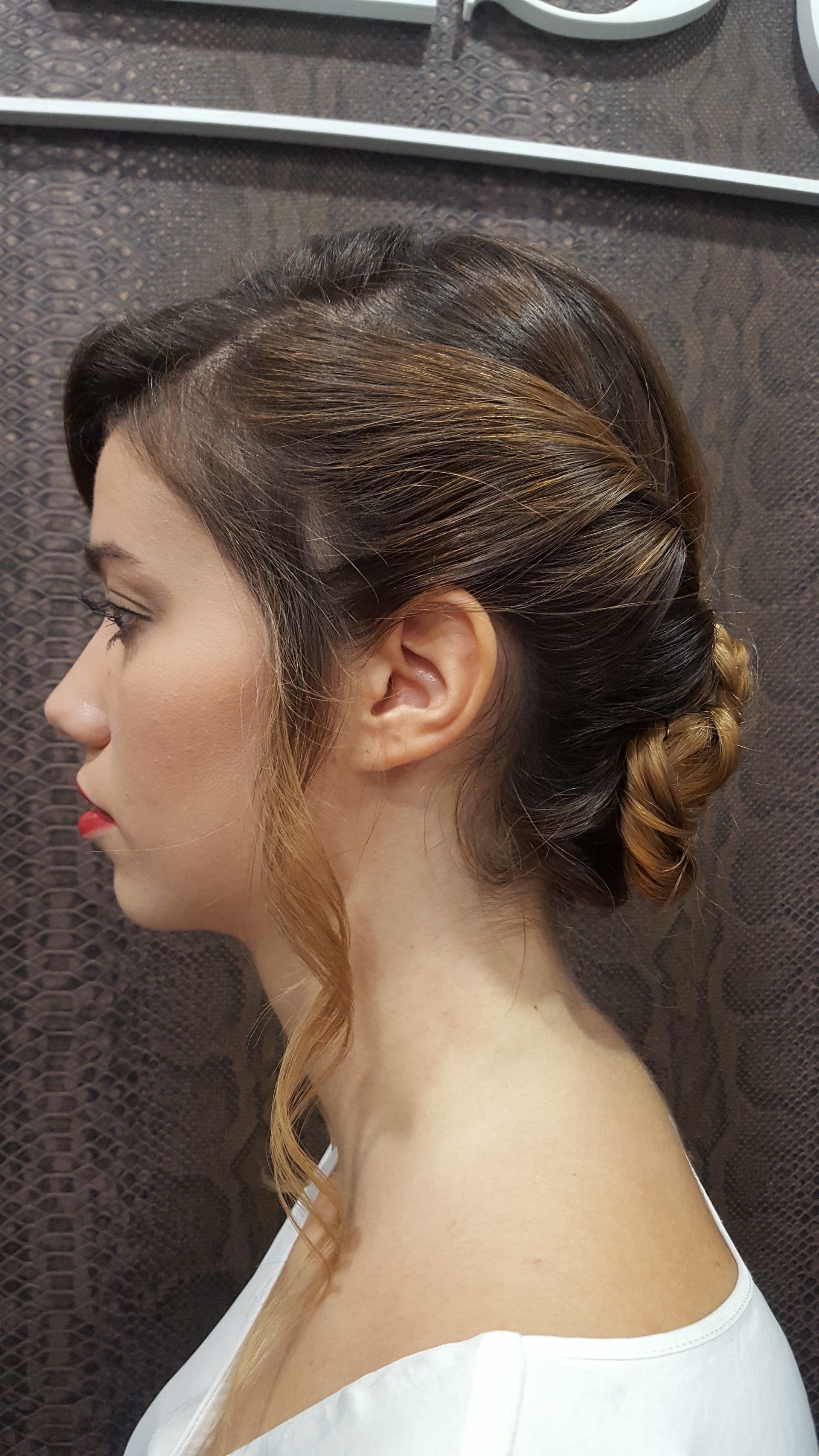 Una mujer con el pelo recogido en un moño lleva una camisa blanca.