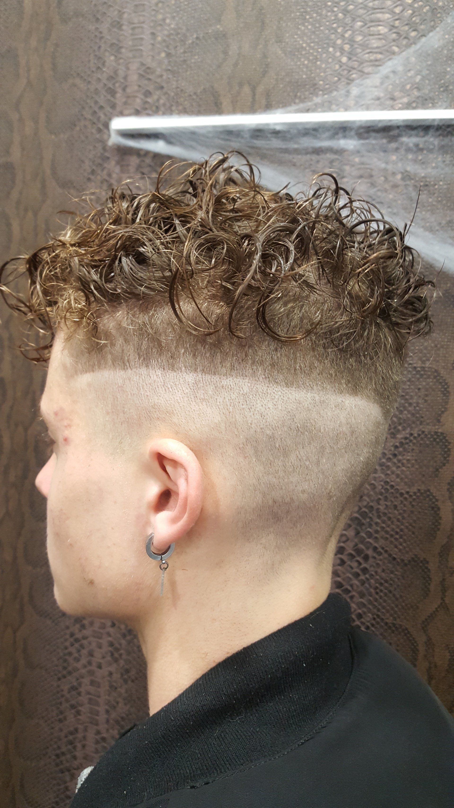 Un joven con cabello rizado se está cortando el pelo.