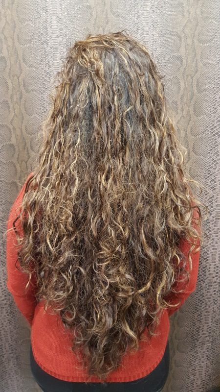 Una mujer con cabello largo y rizado lleva un suéter rojo.