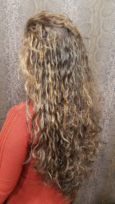 Una mujer con cabello largo y rizado lleva un suéter rojo.