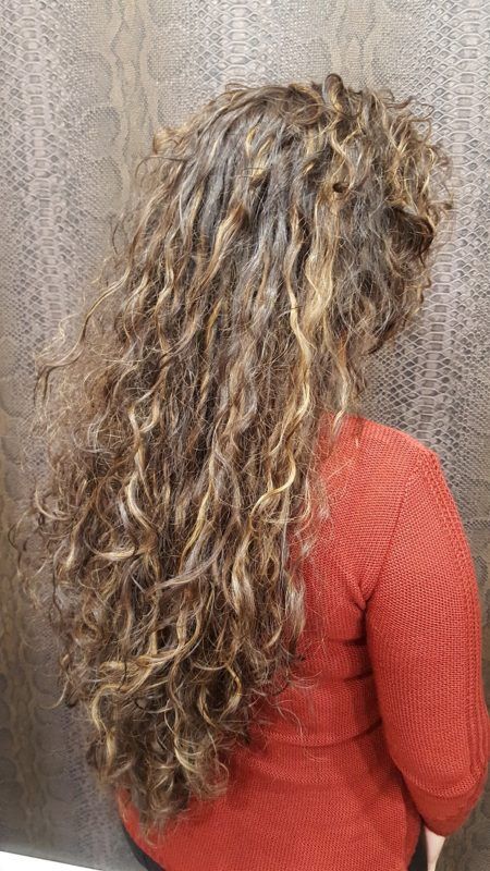 Una mujer con cabello largo y rizado lleva un suéter rojo.