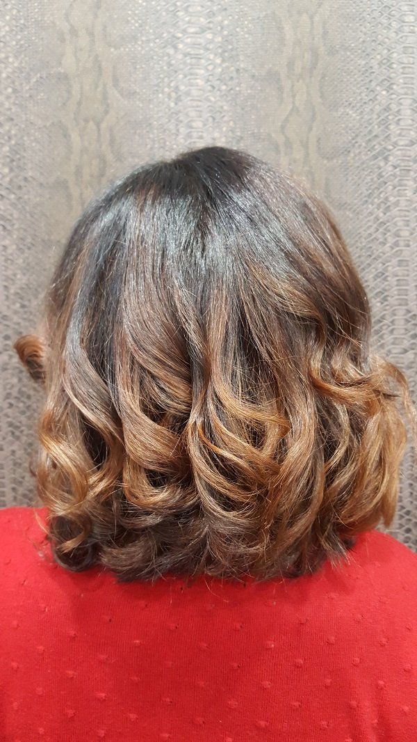 La parte posterior de la cabeza de una mujer con cabello rizado y una camisa roja.