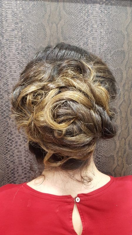 Una mujer lleva una camisa roja y tiene el pelo recogido en un moño.