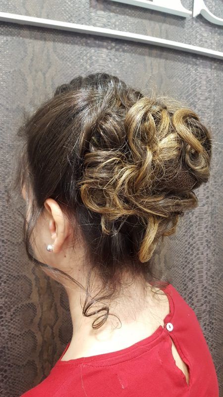 Una mujer lleva una camisa roja y tiene el pelo recogido en un moño.