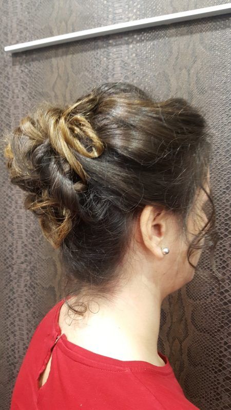 Una mujer lleva una camisa roja y tiene el pelo recogido en un moño.