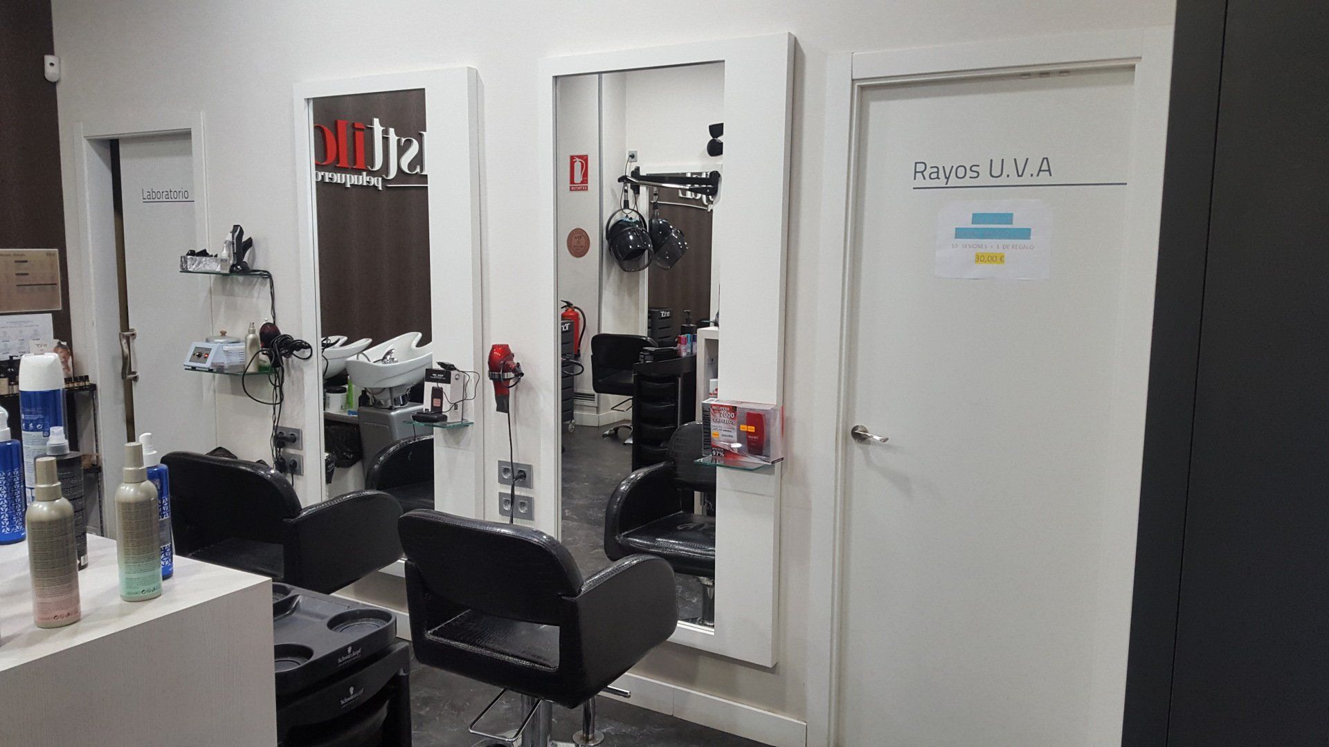 Una peluquería con sillas, espejos y lavabo.