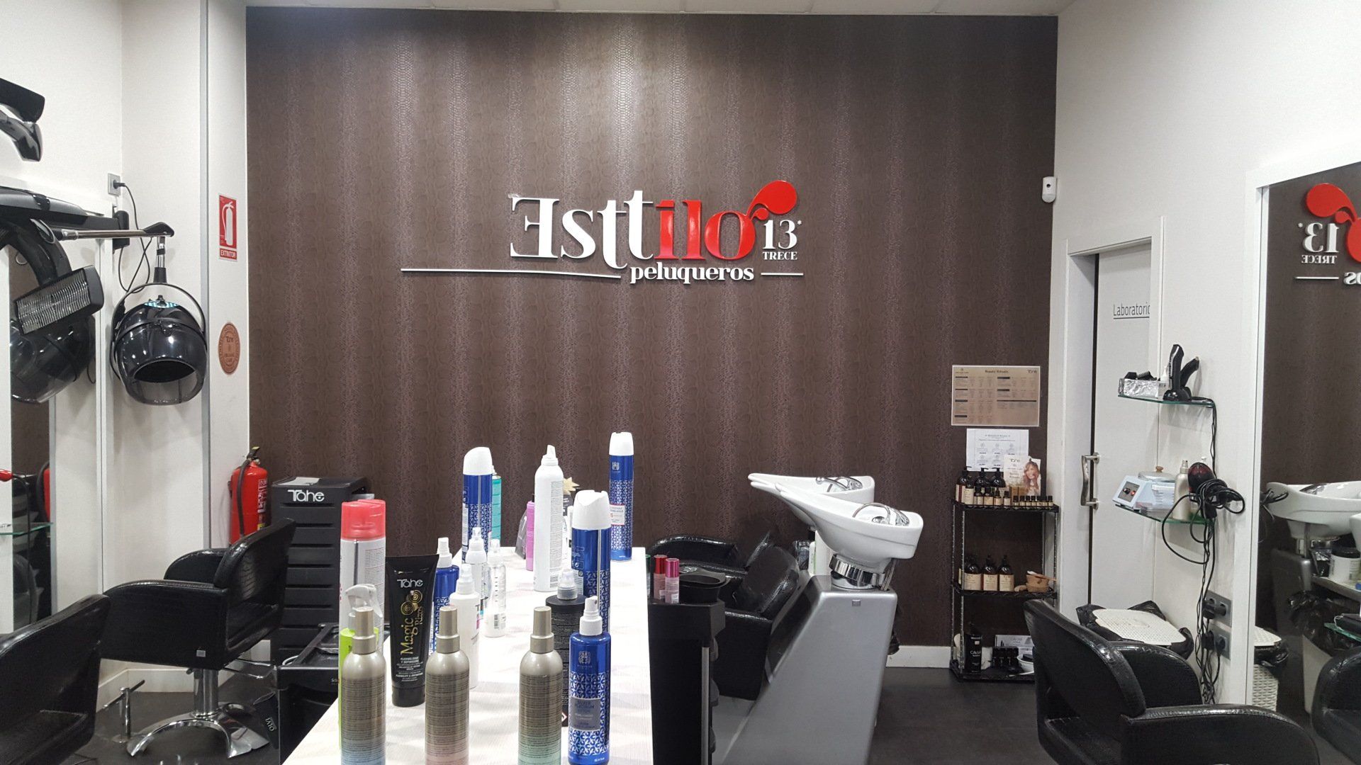 Una peluquería con lavabo, sillas, espejos y frascos de productos para el cabello.