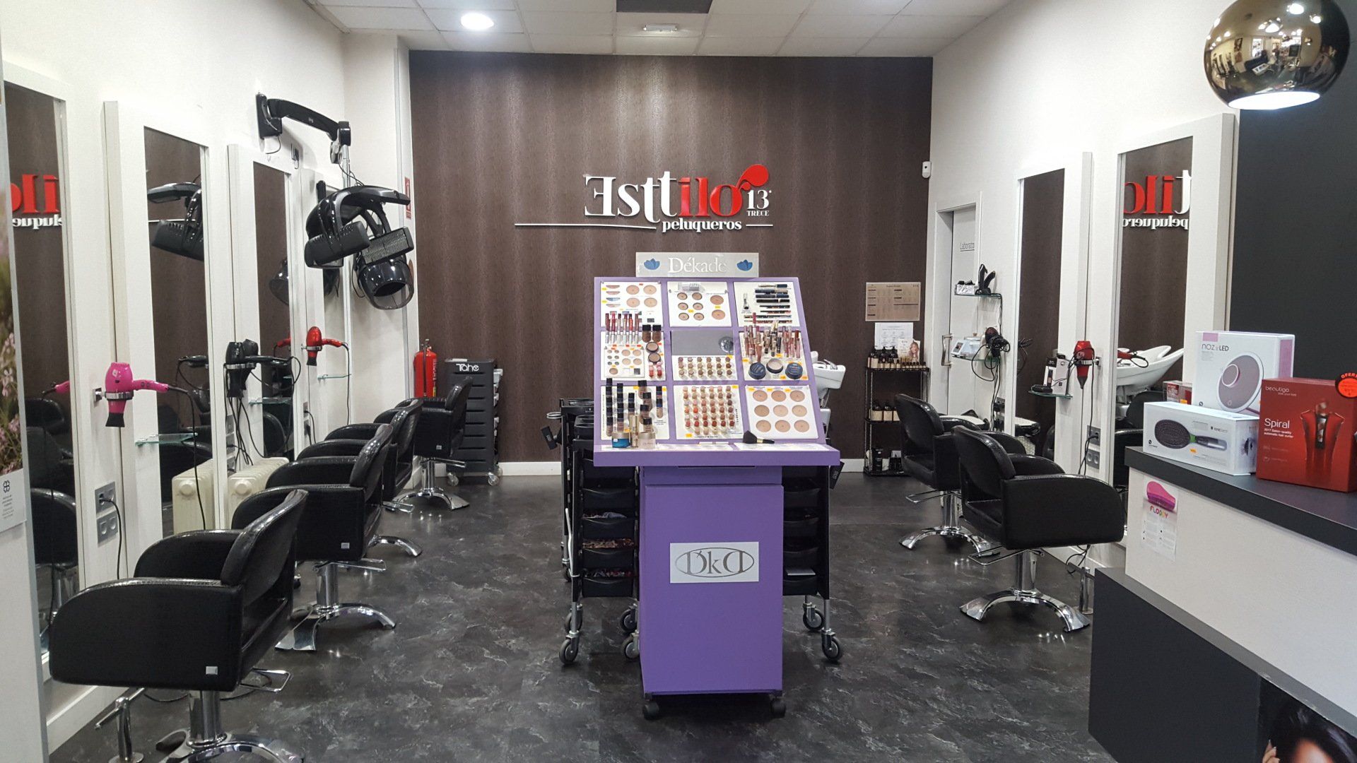 Una peluquería con muchas sillas y un carrito morado.