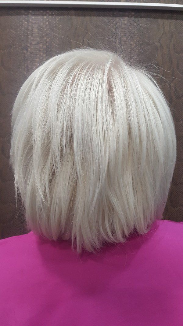 Una mujer con cabello corto y blanco está sentada en una mesa rosa.