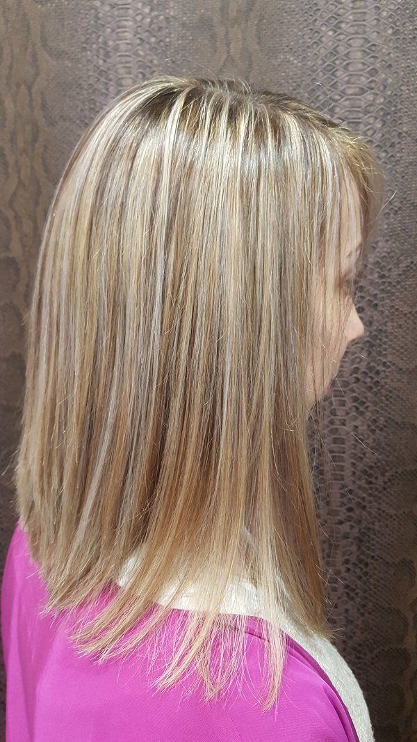 Una mujer con cabello rubio lleva un suéter rosa.