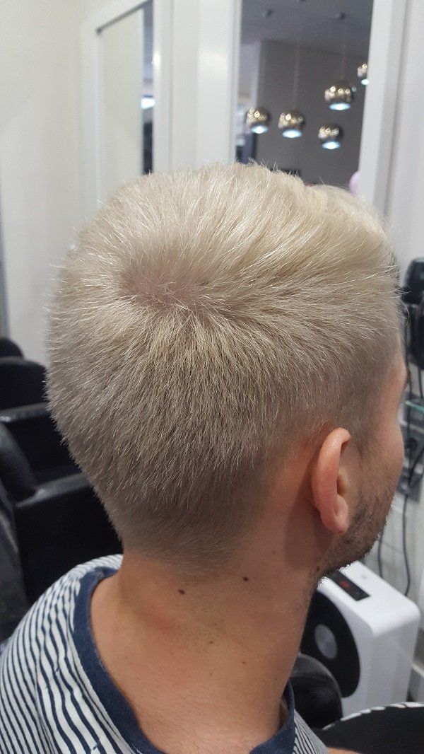 Un hombre con cabello rubio se está cortando el pelo en una peluquería.