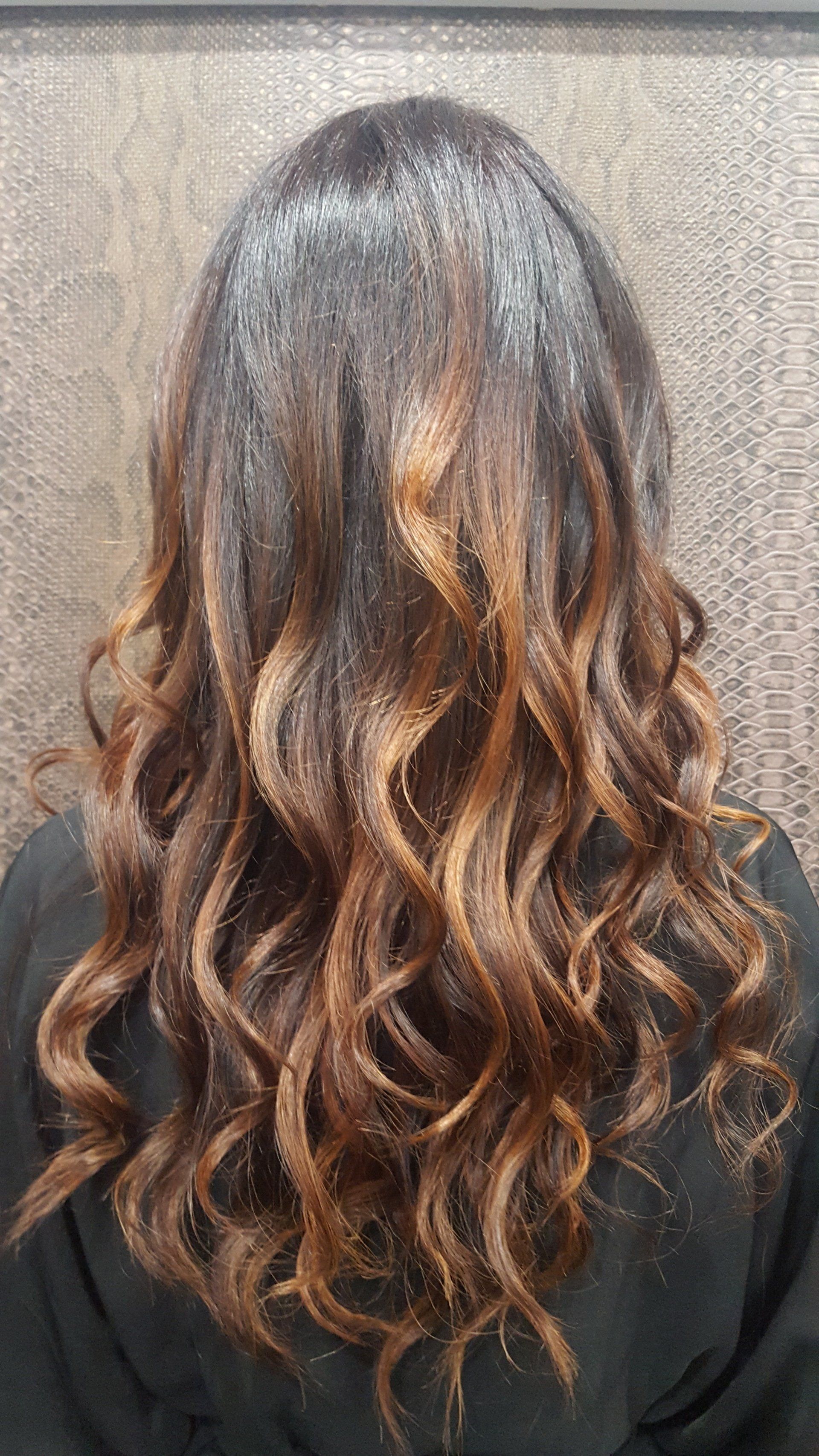 La parte posterior de la cabeza de una mujer con cabello largo y rizado.