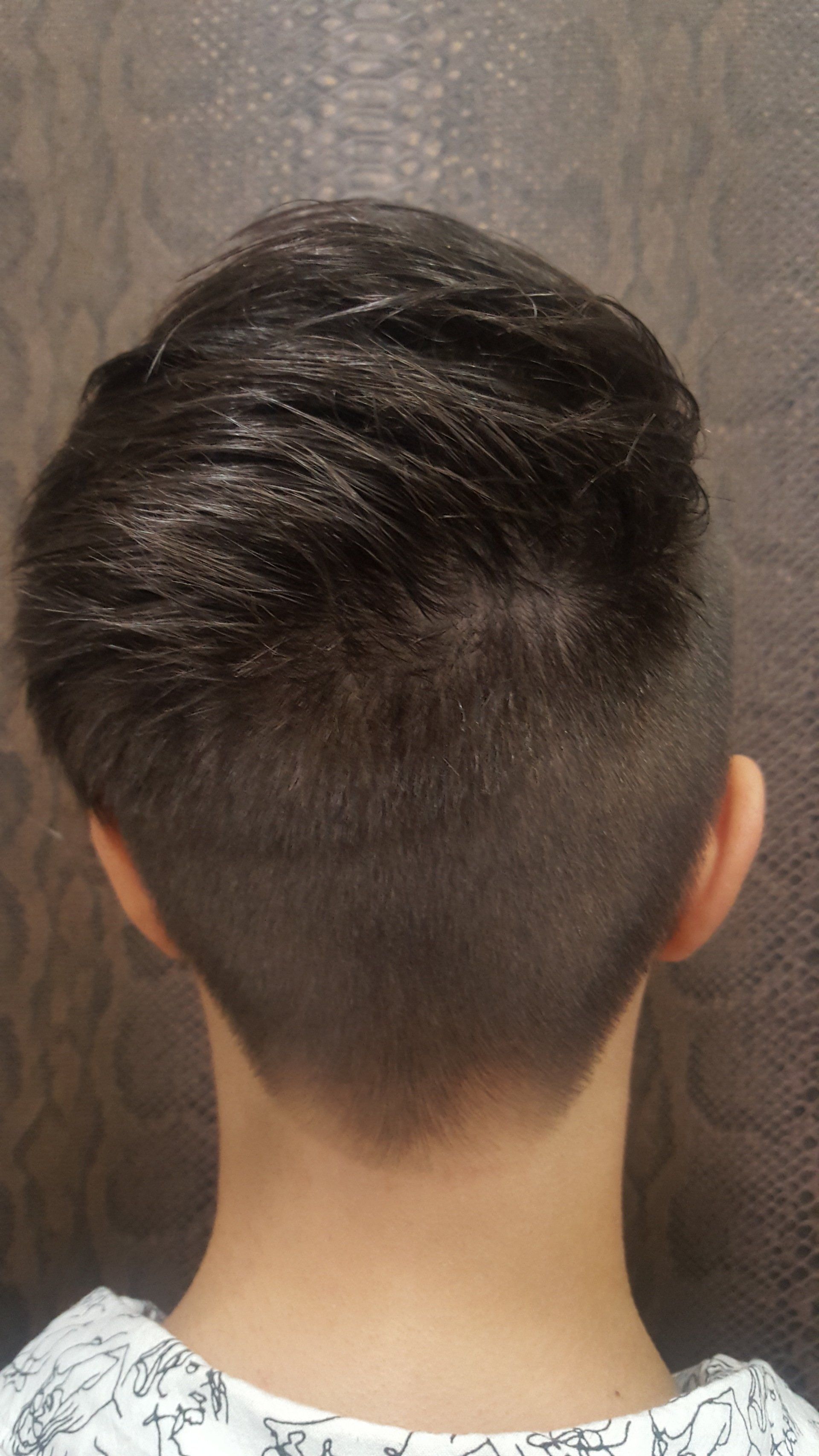 La parte posterior de la cabeza de una persona con un corte de pelo muy corto.