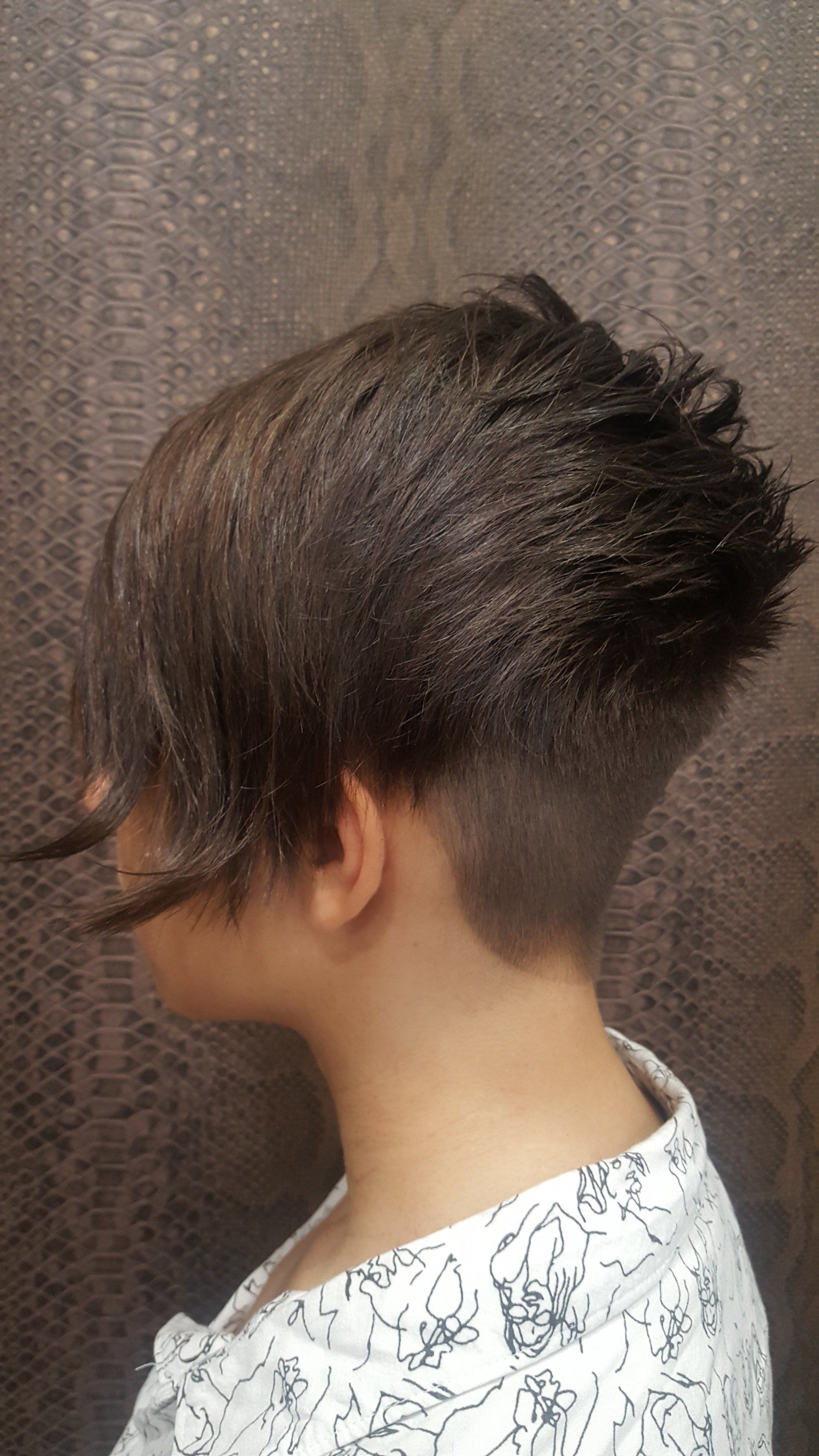 Una mujer con cabello corto y cabeza rapada lleva una camisa blanca.