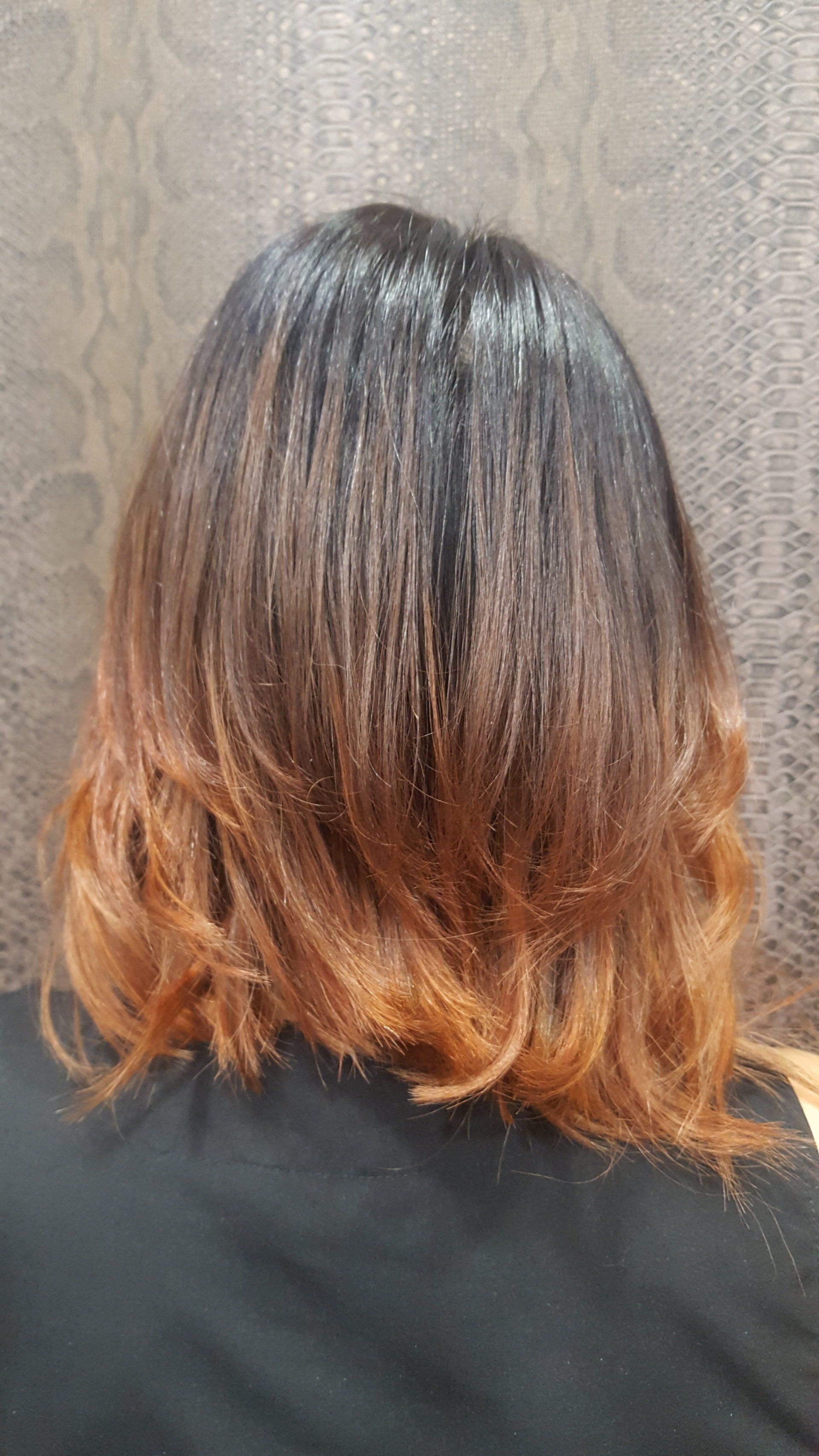 La parte posterior de la cabeza de una mujer con cabello largo y una camisa negra.