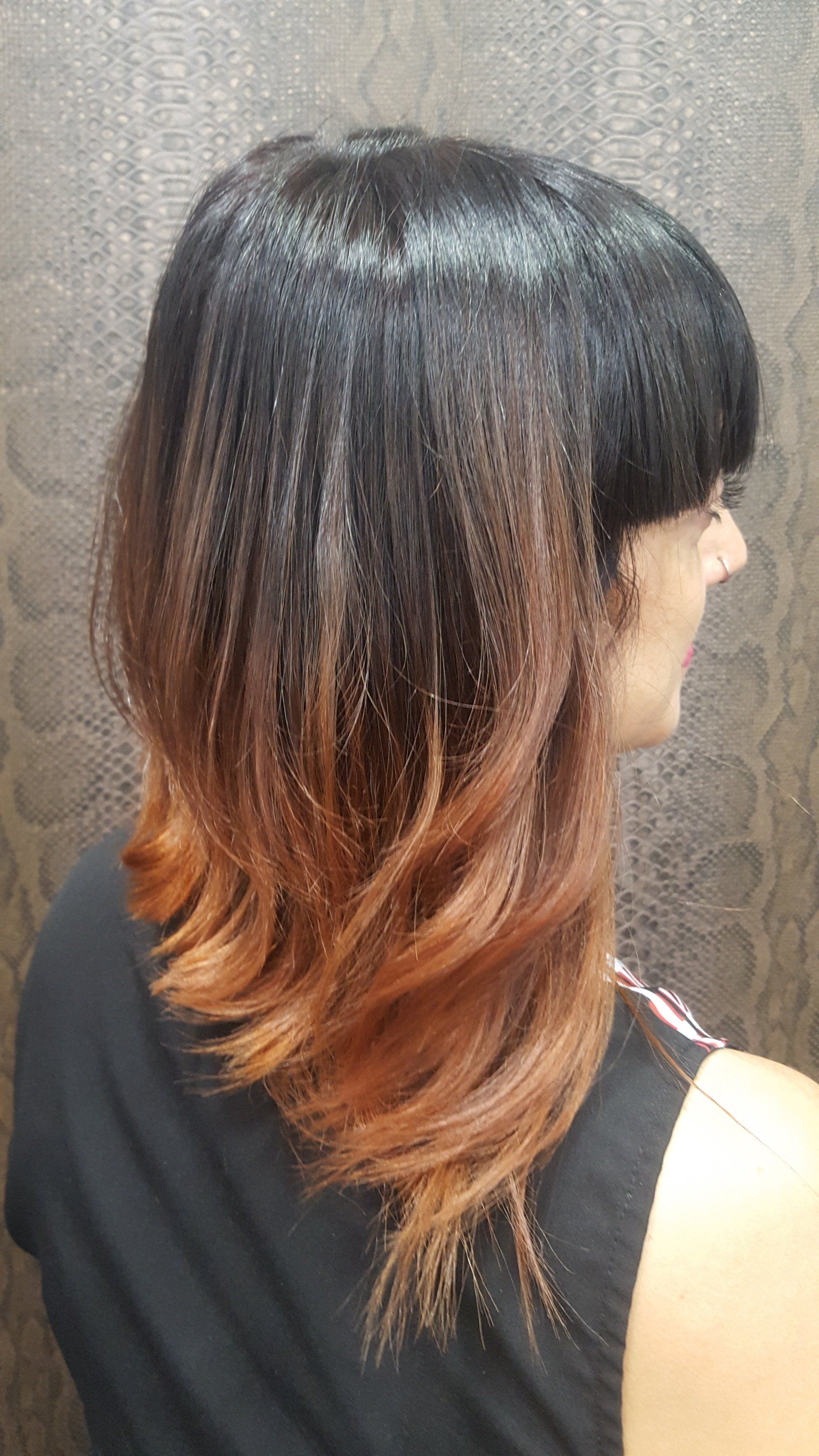 Una mujer con cabello largo negro y castaño lleva una camiseta negra sin mangas.