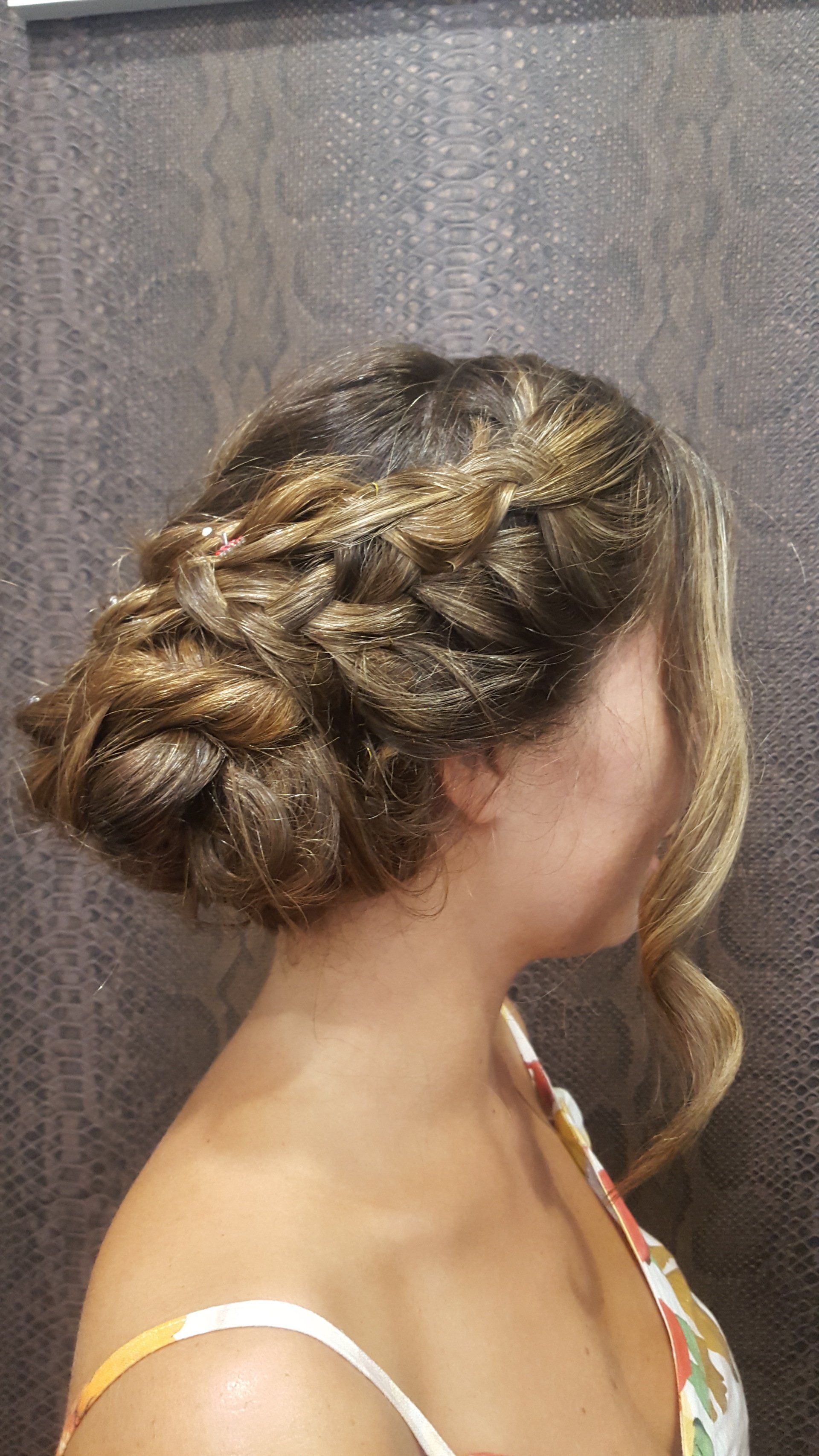 Una mujer que lleva un moño trenzado está parada frente a una pared.