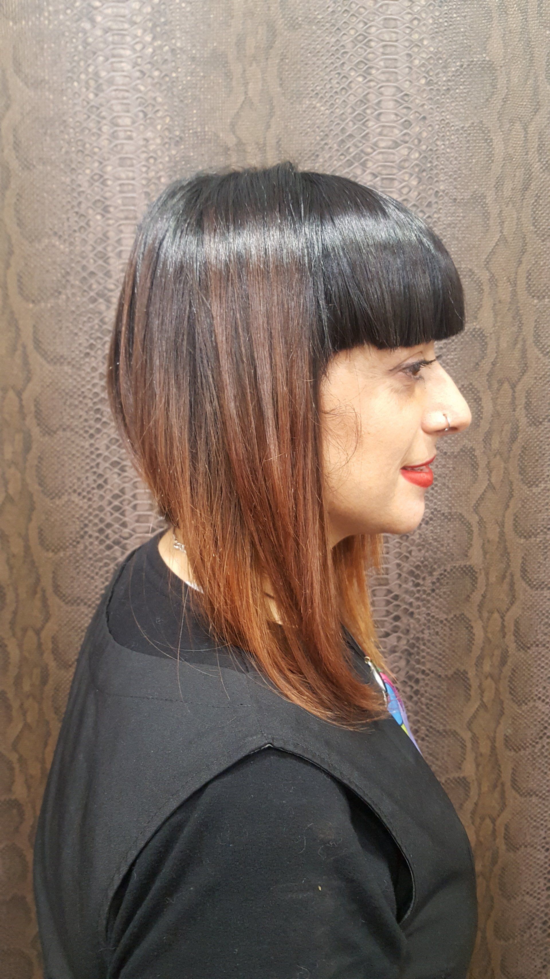 Una mujer con pelo largo y flequillo lleva una camisa negra.