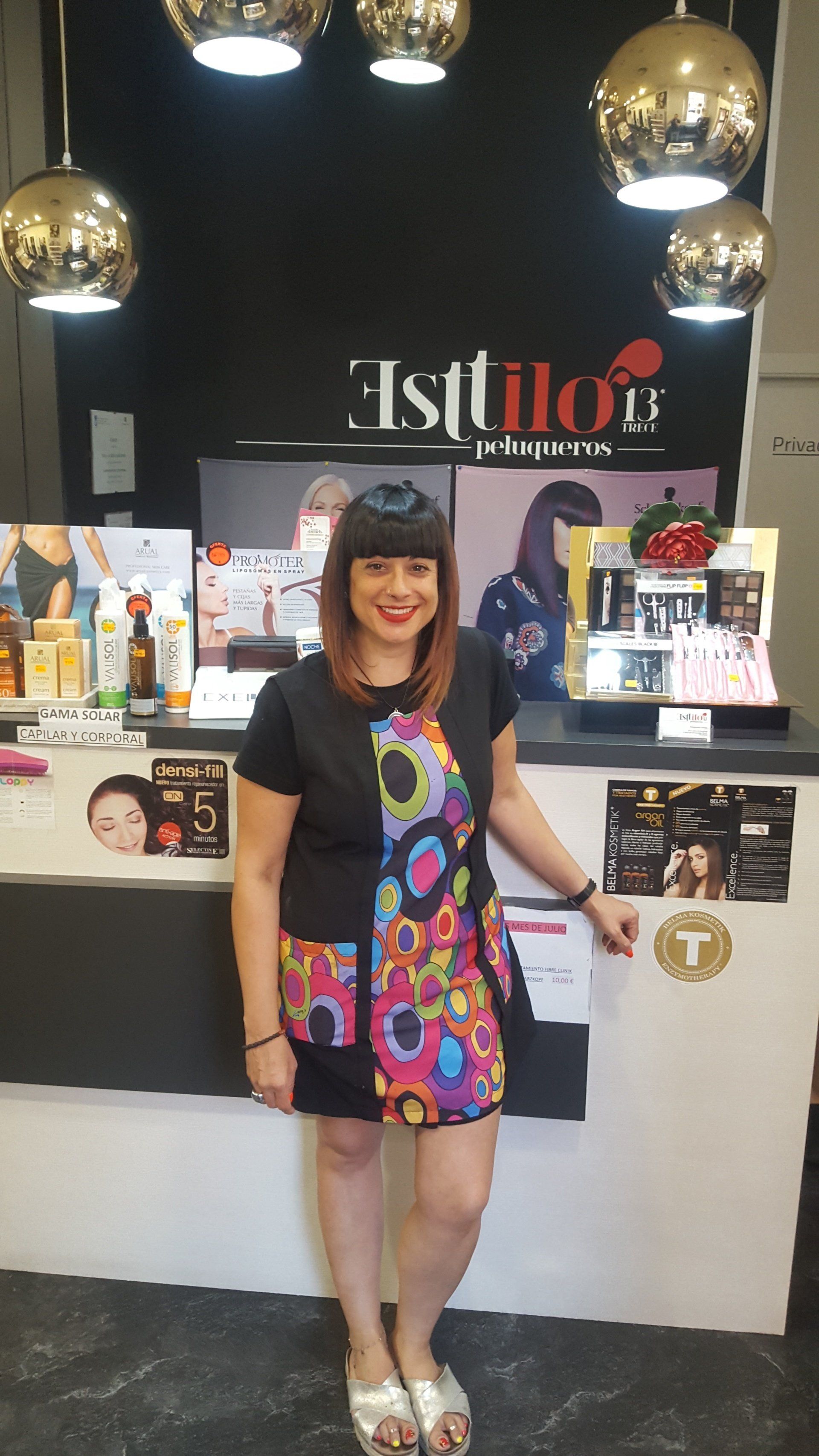 Una mujer con un vestido colorido está parada frente a un mostrador en un salón.