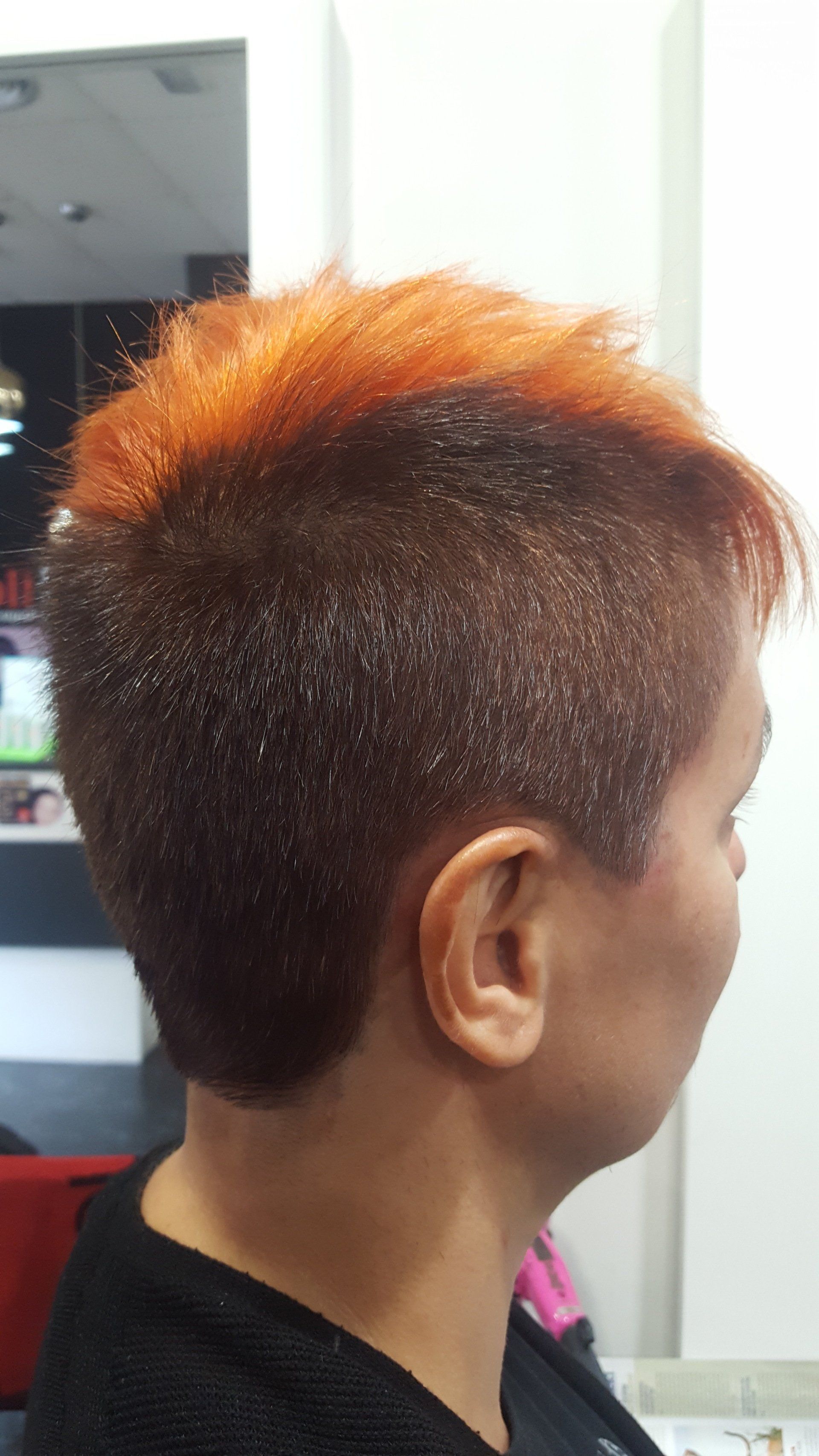 Una mujer con cabello corto y rojo se está cortando el pelo en una peluquería.