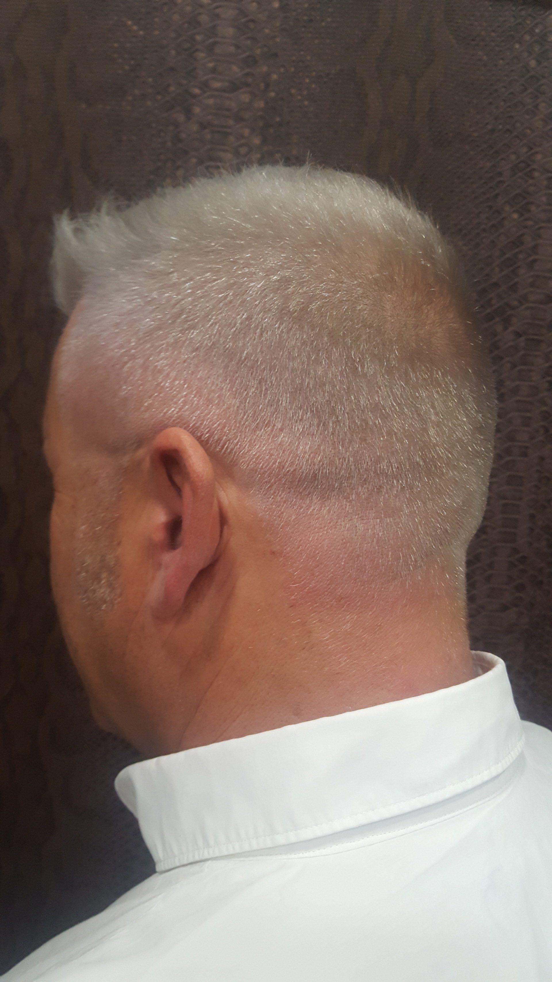 La parte posterior de la cabeza de un hombre con una camisa blanca.