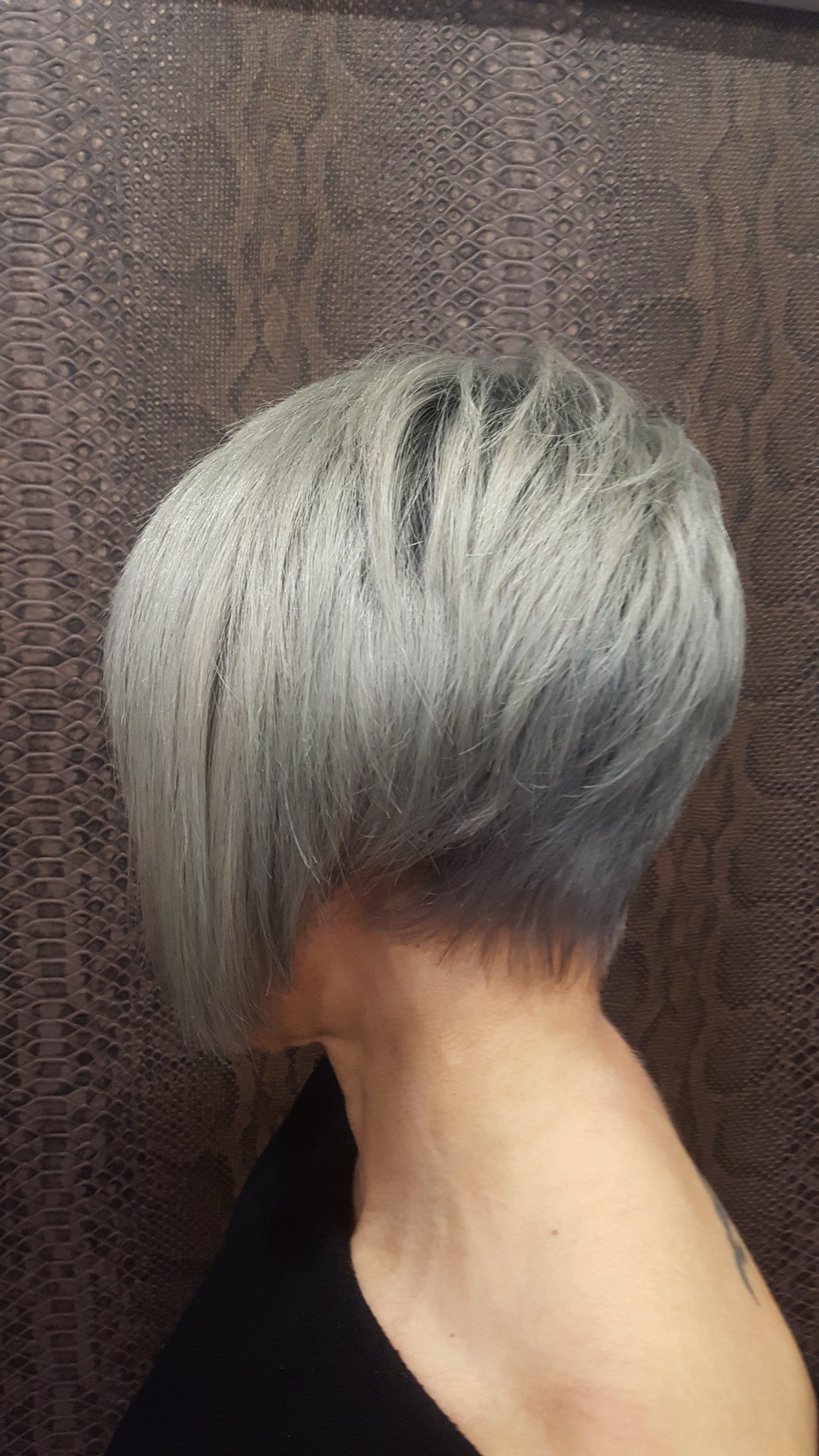 Una mujer con cabello corto y gris lleva una camisa negra.