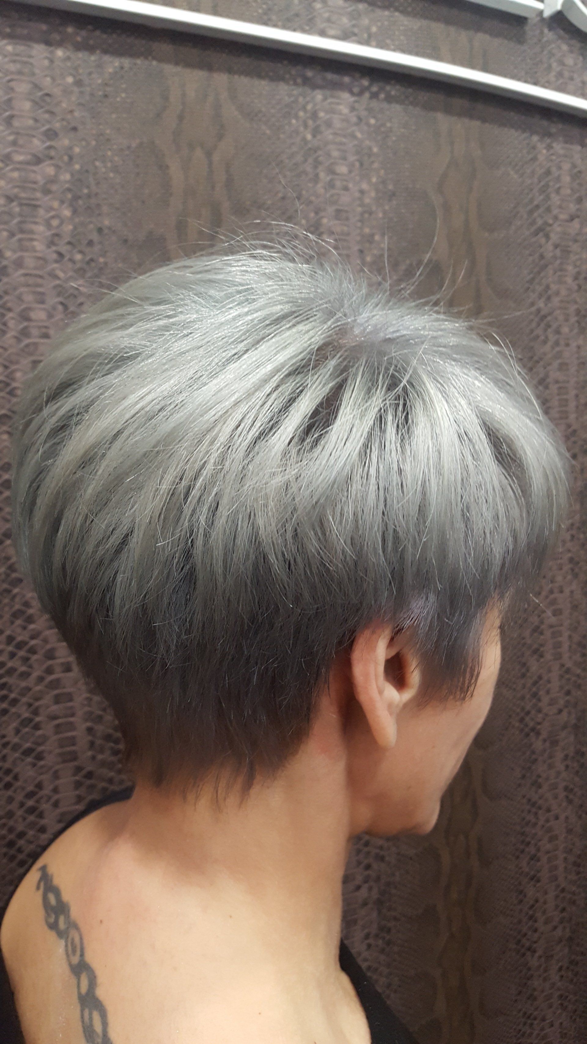 Una mujer con cabello corto y gris y un tatuaje en la espalda.